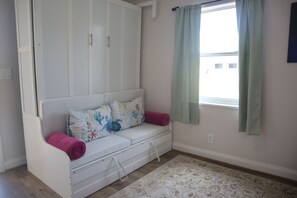 A room with a white sofa, a patterned rug, and a window with light green curtains. - Lauderdale Breeze Villas (Fort Lauderdale)