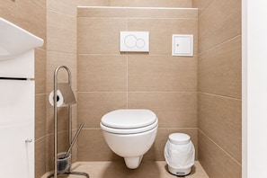 Un baño moderno con inodoro, bidé y secador de manos.