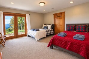 A bedroom with two beds, a sliding glass door to a balcony, and a wooden door with a coat rack. - Kumbaya House: Steps from Cupp Run | Hot Tub, Deck & Epic Sunset Views (Snowshoe)