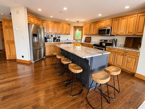 Une cuisine moderne avec des meubles en bois, des appareils en acier inoxydable et un îlot central doté de tabourets.