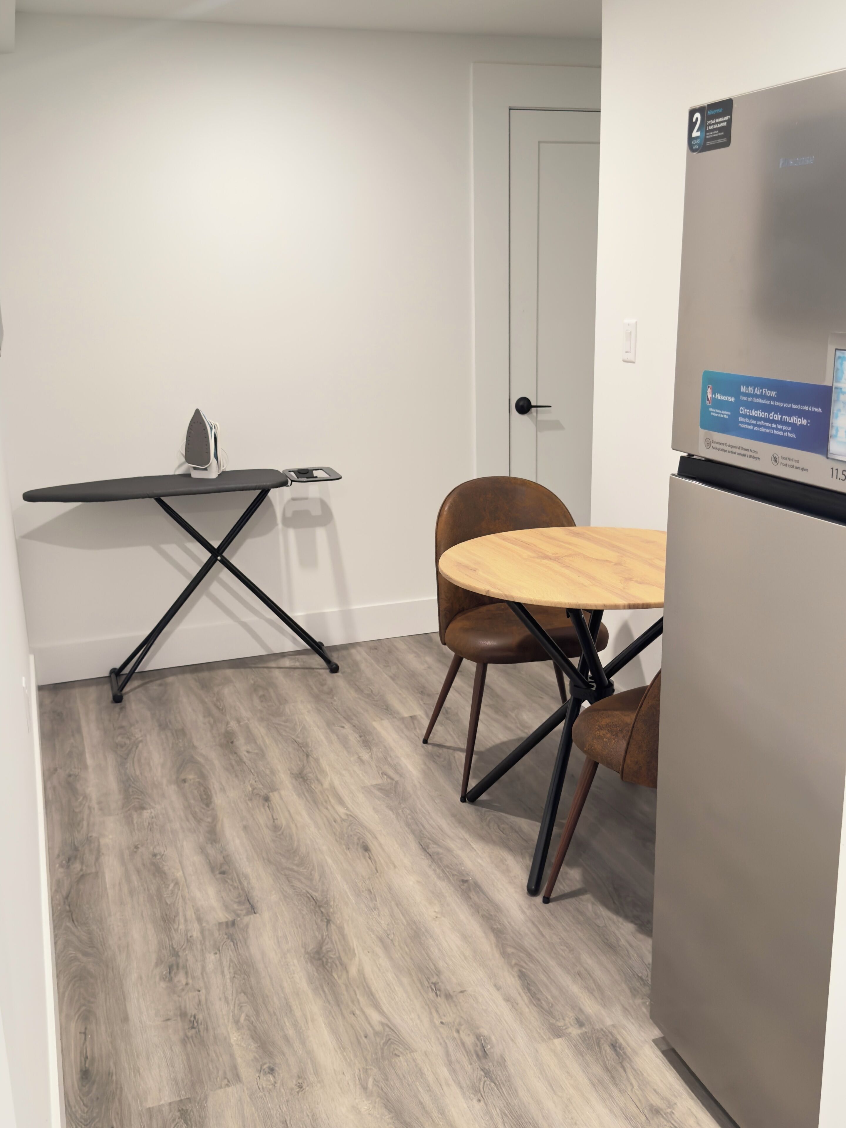 A compact kitchen with a wooden dining table, a single chair, and a built-in refrigerator.