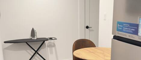 A compact kitchen with a wooden dining table, a single chair, and a built-in refrigerator.