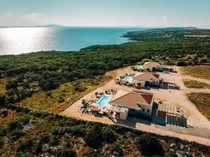 A coastal property with multiple buildings, a swimming pool, and a view of the sea. - 5* Luxury Seaview Villa Plant 4 with pool by Interhome (Novalja)