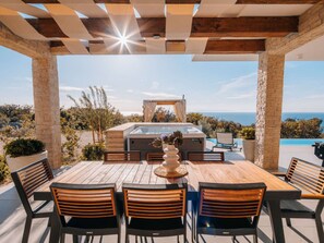 Eine Außenpatio mit Whirlpool, Sitzgelegenheit und Meerblick.