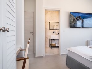 Un baño moderno con lavamanos de mármol, un espejo y un cuadro en la pared.