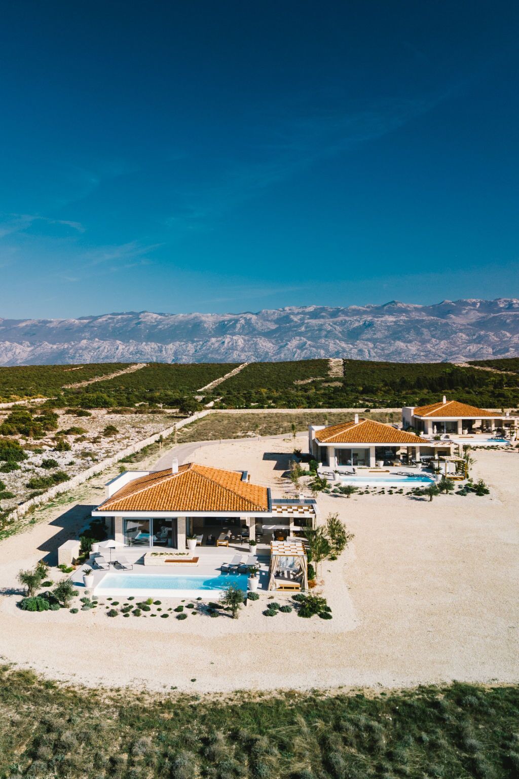 Un complexe hôtelier comprenant plusieurs villas, chacune dotée d’une piscine et offrant une vue sur les montagnes.