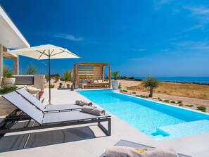A pool area with lounge chairs, a pergola, and a view of the sea. - 5* Luxury Seaview Villa Plant 3 with pool by Interhome (Novalja)