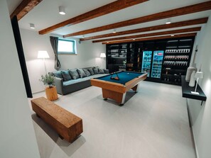 A modern living room with a pool table, a sofa, a coffee table, and a bar area with shelves of bottles. - 5* Luxury Seaview Villa Plant 1 with pool by Interhome (Novalja)