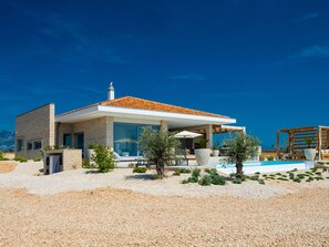 A modern house with a pool, outdoor seating, and a clear blue sky. - 5* Luxury Seaview Villa Plant 1 with pool by Interhome (Novalja)