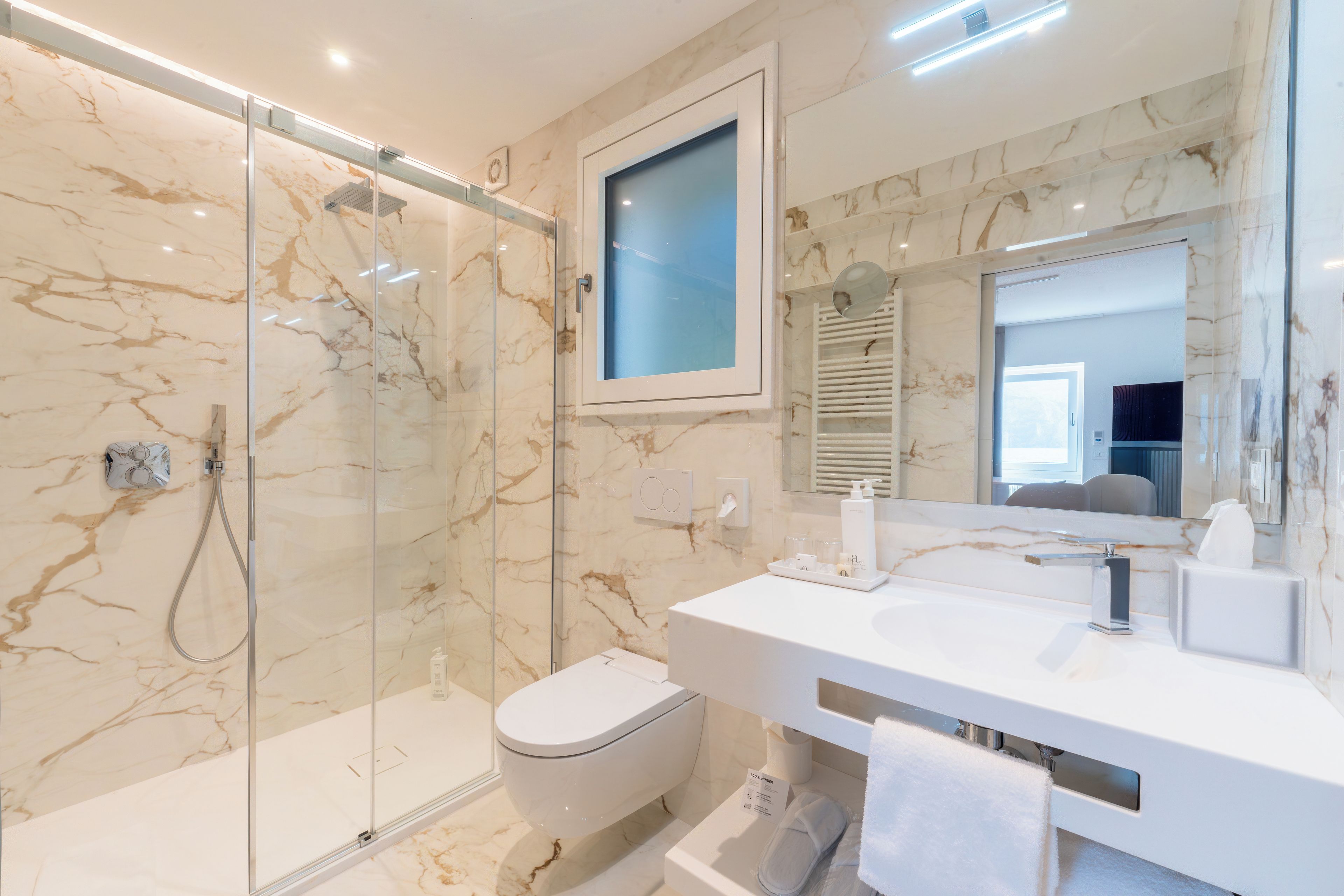 A modern bathroom with a glass-enclosed shower, a white toilet, and a vanity with a mirror.