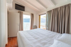 Habitación de hotel con cama, televisor, puerta y vista al mar.