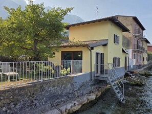Un edificio amarillo con balcón, una pared de piedra y un río.