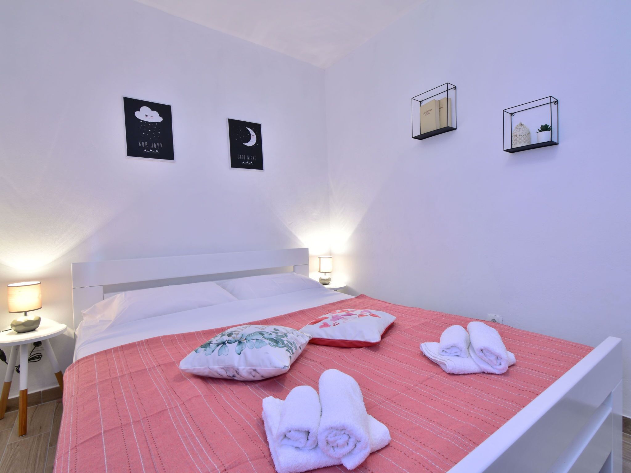 A hotel room with a bed, pillows, a nightstand, wall art, and a bedside lamp.