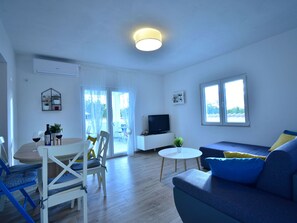 A modern living room with a dining area, a flat-screen TV, and a large window providing natural light. - Holiday Home Dinko with pool by Interhome (Pridraga)