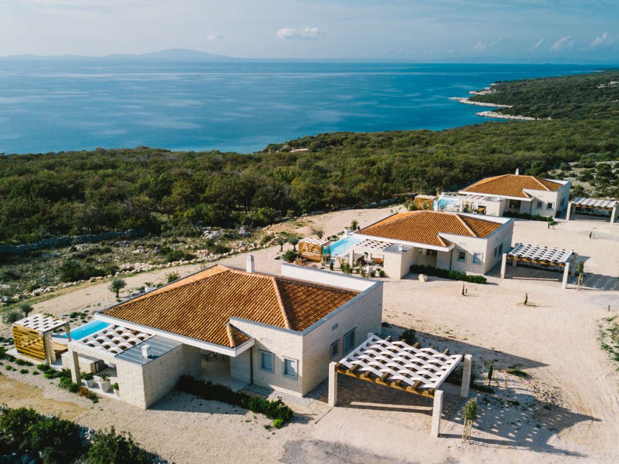 Une propriété située sur la côte, comprenant plusieurs bâtiments, une piscine et offrant une vue sur la mer.