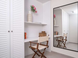 Une salle de bain moderne avec des meubles blancs, un meuble-lavabo doté d’un miroir et une chaise en bois.