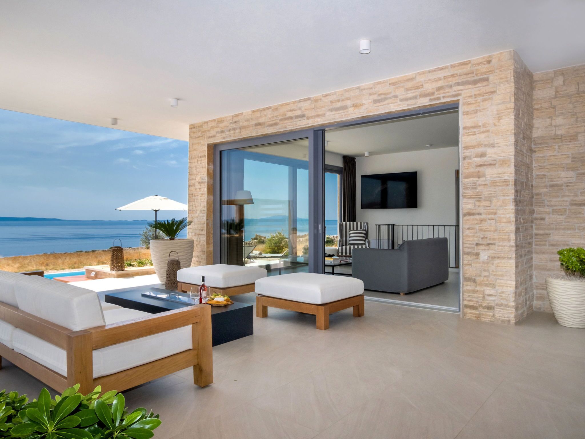 Un salon moderne avec vue sur la mer, comprenant un canapé, une table basse et un téléviseur.