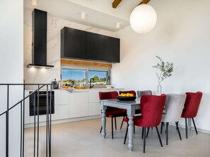 Een moderne keuken met een eethoek, met een marmeren werkblad, zwarte kastjes en uitzicht op het buitengebied.