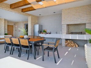 A modern outdoor kitchen with a dining area, stone walls, and a fireplace. - 5* Luxury Seaview Villa Plant 5 with pool by Interhome (Novalja)