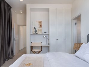 Une chambre à coucher avec un lit, une table de chevet, une lampe, une armoire et un tableau au mur.