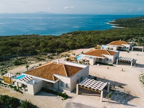 A coastal property with multiple buildings, a swimming pool, and a view of the sea. - 5* Luxury Seaview Villa Plant 5 with pool by Interhome (Novalja)