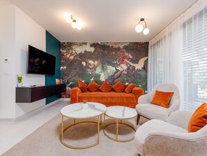 A modern living room with a large mural, two round tables, a sofa, and a TV mounted on the wall. - Luxury Apartment Infinity Blue A1 by Interhome (Zadar)