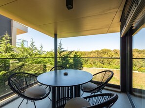 A modern outdoor dining area with a round table and four chairs, overlooking a lush landscape. - Luxury Apartment Infinity Blue A1 by Interhome (Zadar)