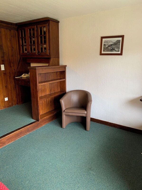 A room with a wooden cabinet, a leather chair, and a framed picture on the wall.