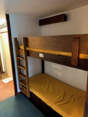 Un lit superposé avec une structure en bois et un matelas jaune.