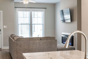 Een moderne woonkamer met een bank, een flatscreen televisie aan de muur en een open haard.