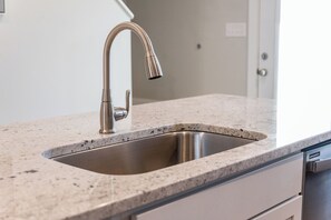 Eine Küche mit einem Edelstahl-Spülbecken, einer Granit-Arbeitsplatte und einem weißen Schrank.
