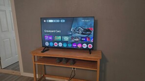 A television on a wooden stand displaying a car advertisement and various app icons.