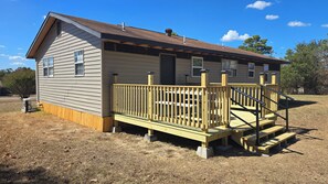 A small, single-story building with a wooden deck and a staircase leading to a covered porch.
