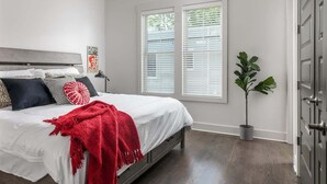 A bedroom with a bed, a nightstand, a potted plant, and a window with blinds. - E. Nash 3BR Escape | Walkable | Family Friendly (Nashville)