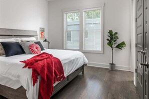 A bedroom with a bed, a nightstand, a potted plant, and a window with blinds. - E. Nash 3BR Escape | Walkable | Family Friendly (Nashville)