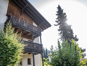 Un bâtiment à deux étages doté d’un balcon, entouré de verdure et d’arbres.