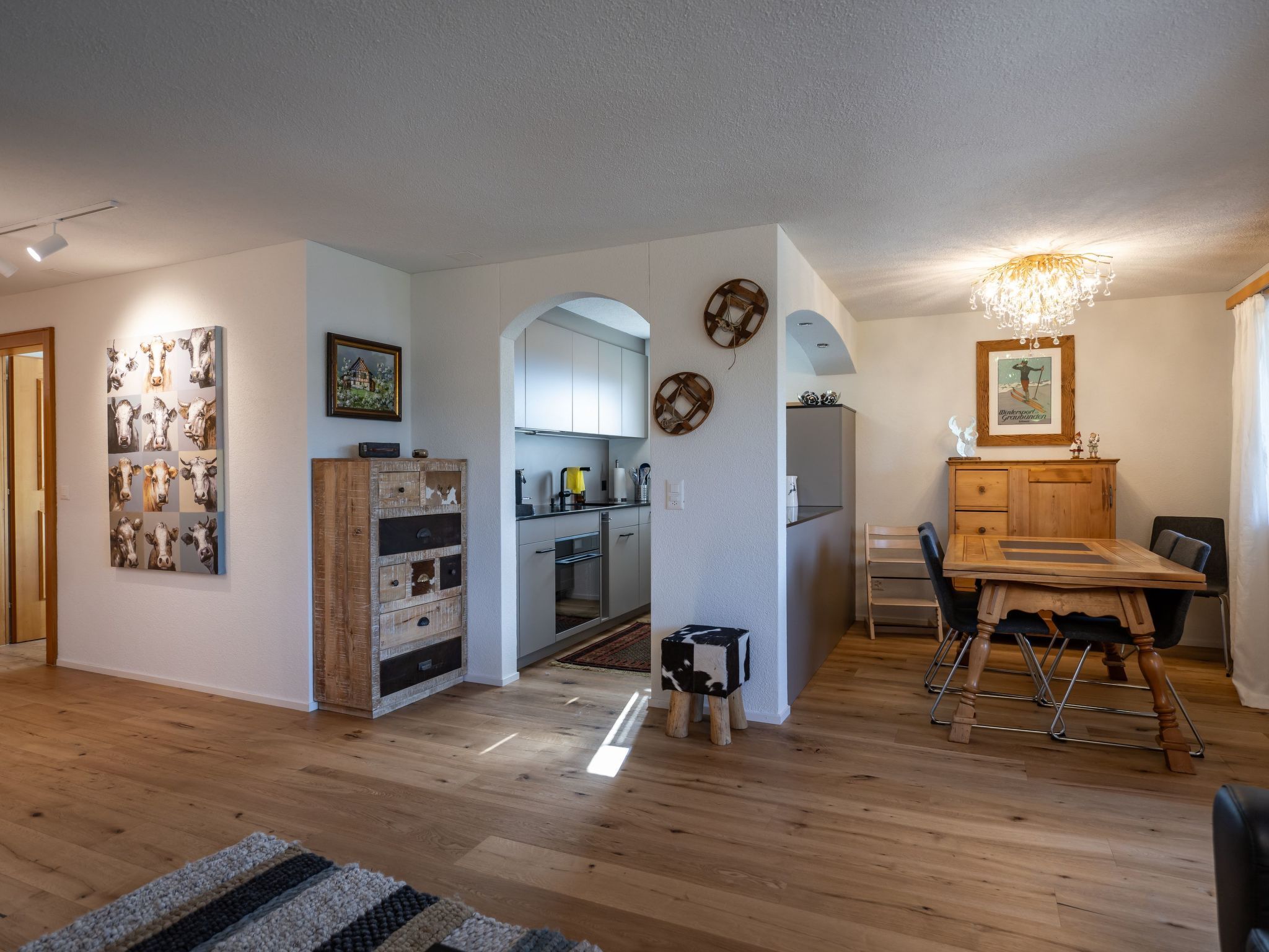 A spacious living area with a wooden dining table, a kitchen with modern appliances, and a cozy seating area.