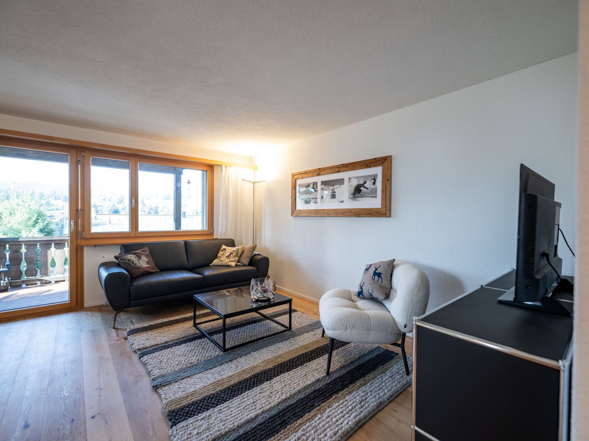 Een moderne woonkamer met een bank, fauteuil, salontafel en een televisie.