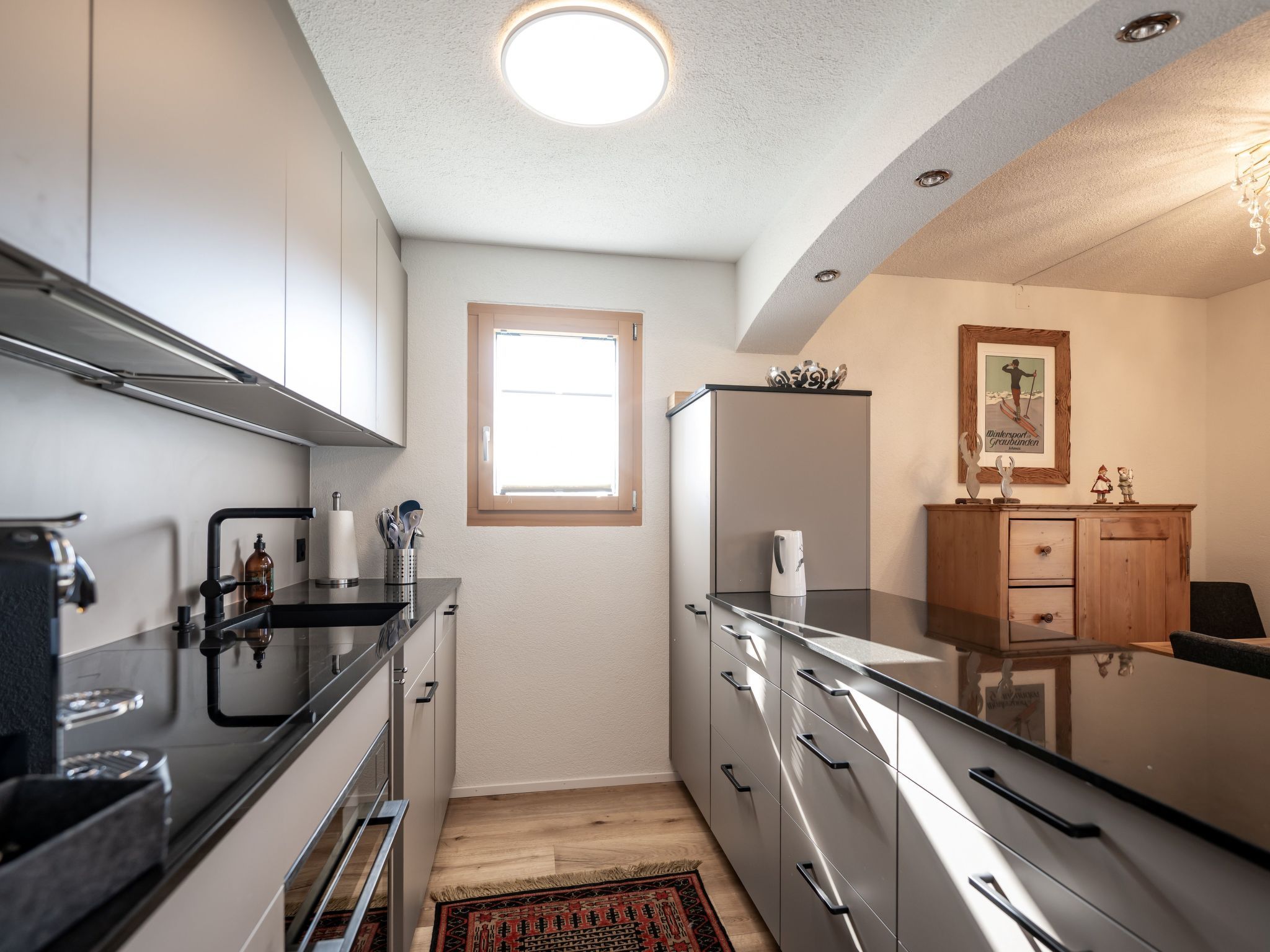 A modern kitchen with stainless steel appliances, wooden cabinets, and a window providing natural light.