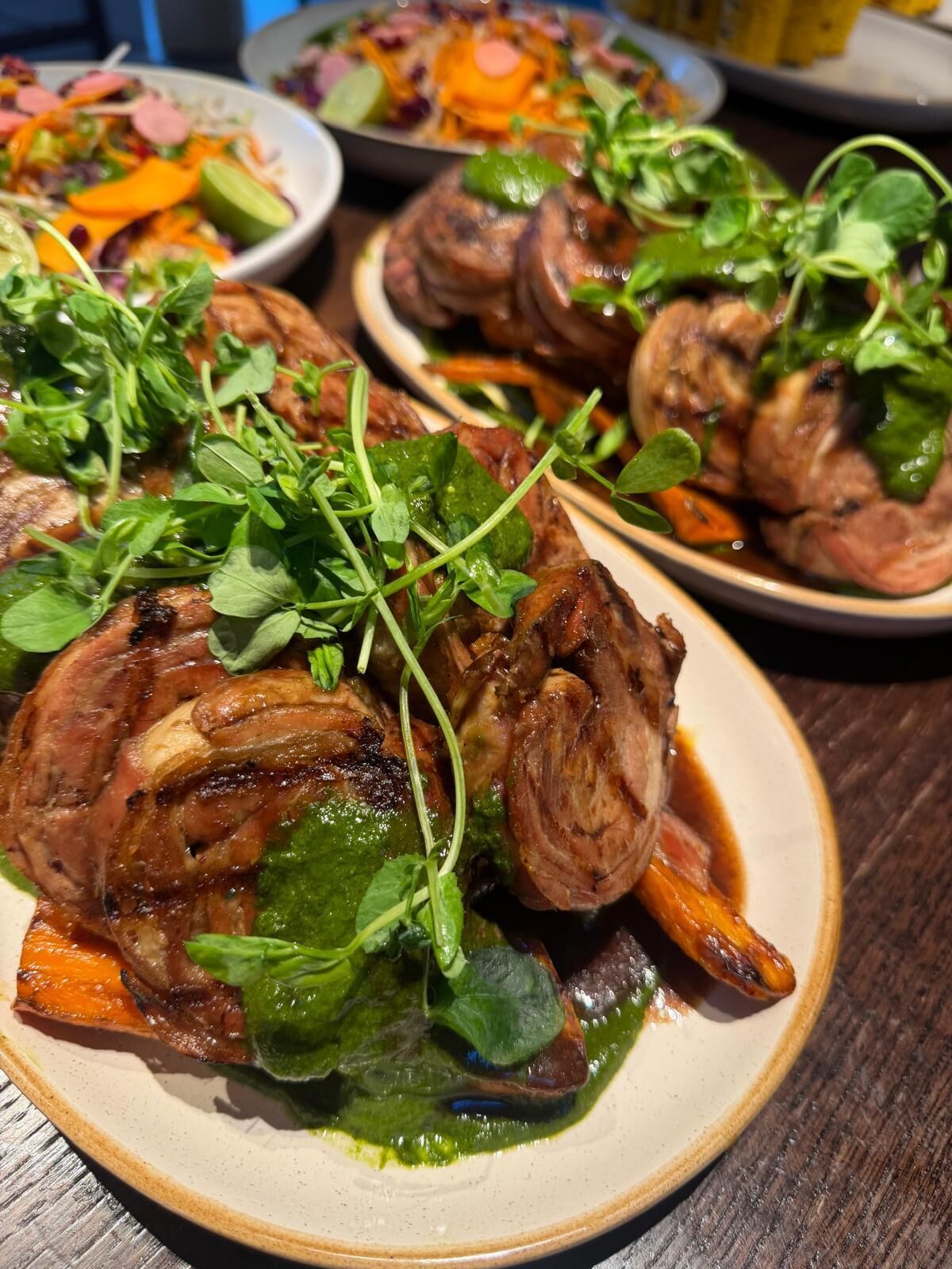 A plate of roasted meat with vegetables and greens.