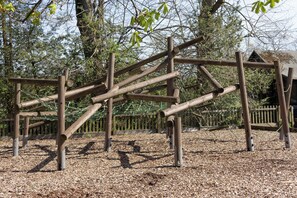 A playground with wooden climbing structures and a wooden fence in the background.
