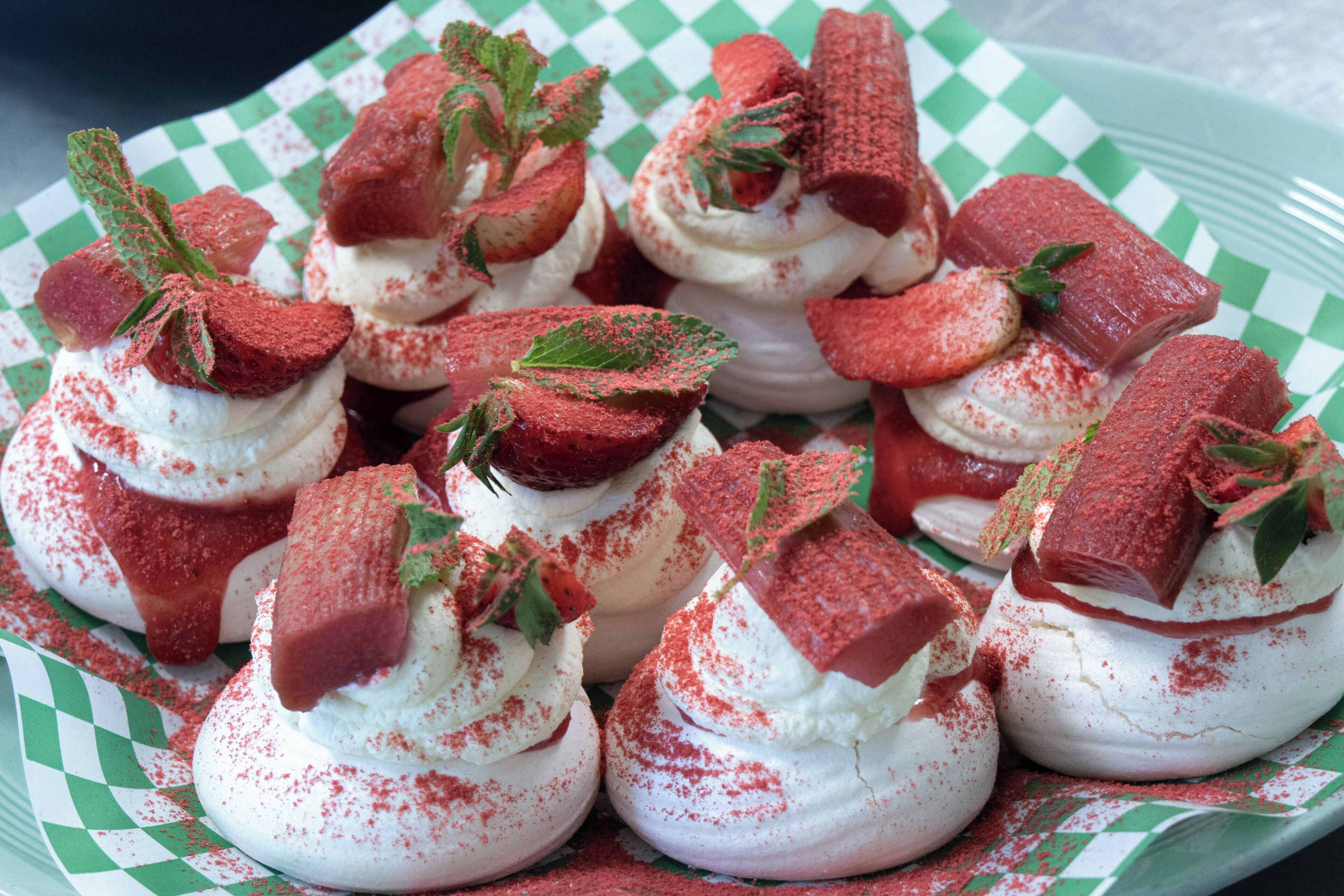 A plate of dessert with whipped cream, strawberries, and a red powder.