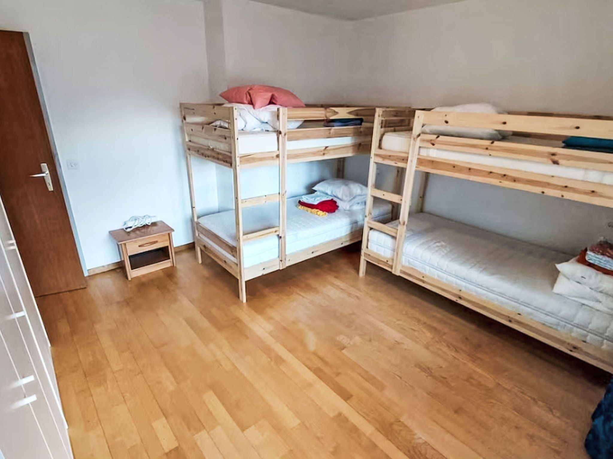 A bunk bed room with a small wooden nightstand and a door.