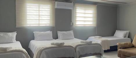 A hotel room with two single beds, a chair, and a window with blinds.