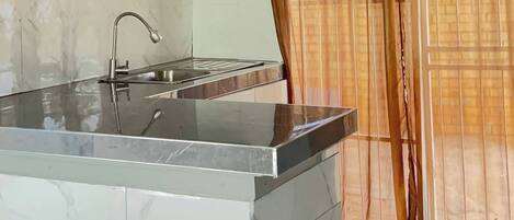 A kitchen with a marble countertop, a sink, and cabinets.