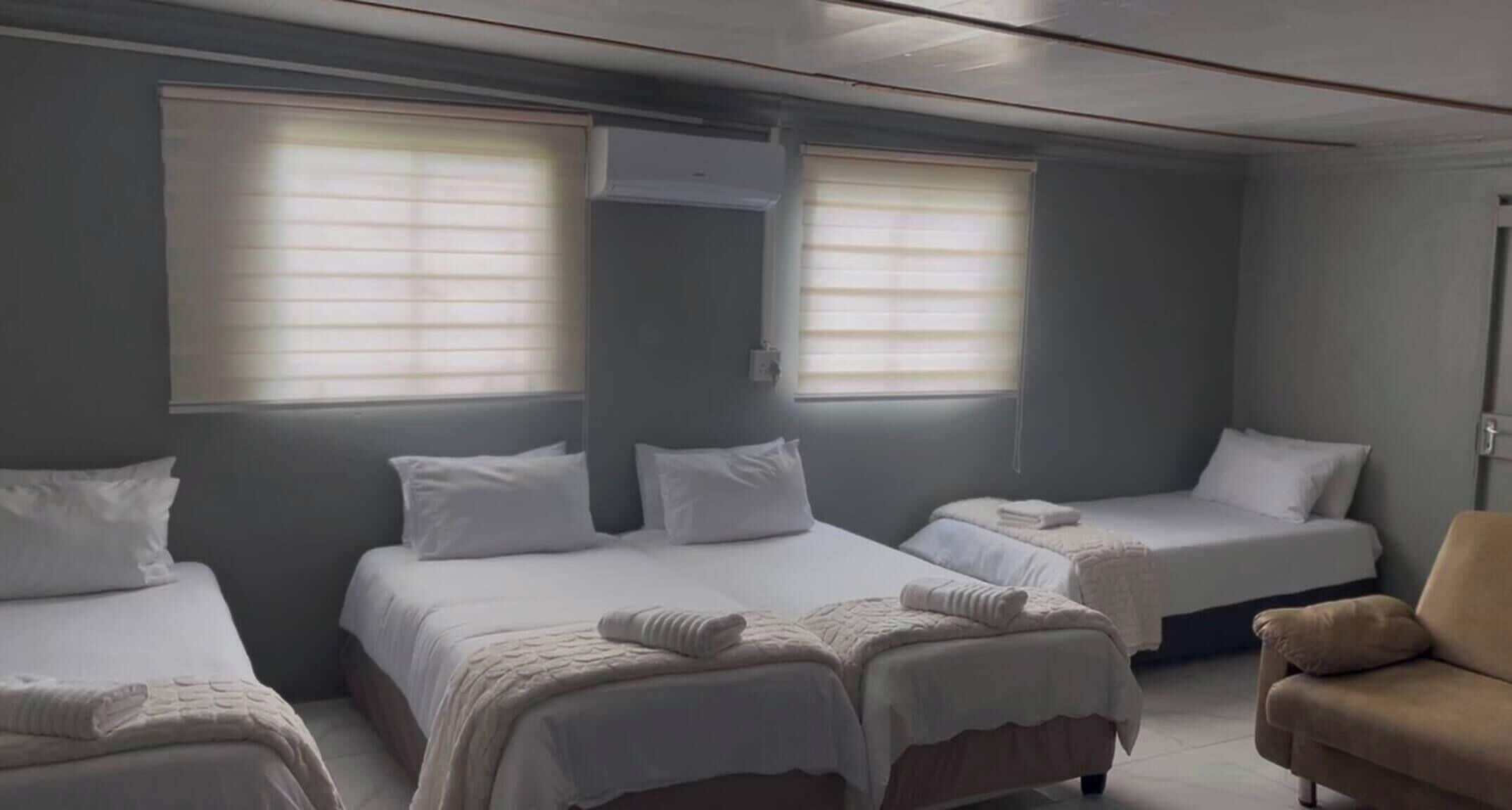 Une chambre d’hôtel avec trois lits, un canapé et un fauteuil.