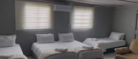 Habitación de hotel con tres camas, un sofá y una silla.