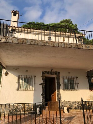A two-story building with a stone facade, a balcony with a railing, and a door with a stone lintel. - Villa for 8 to 10 people in Lloret de Mar with a pool—6 km from the beach (CT)
