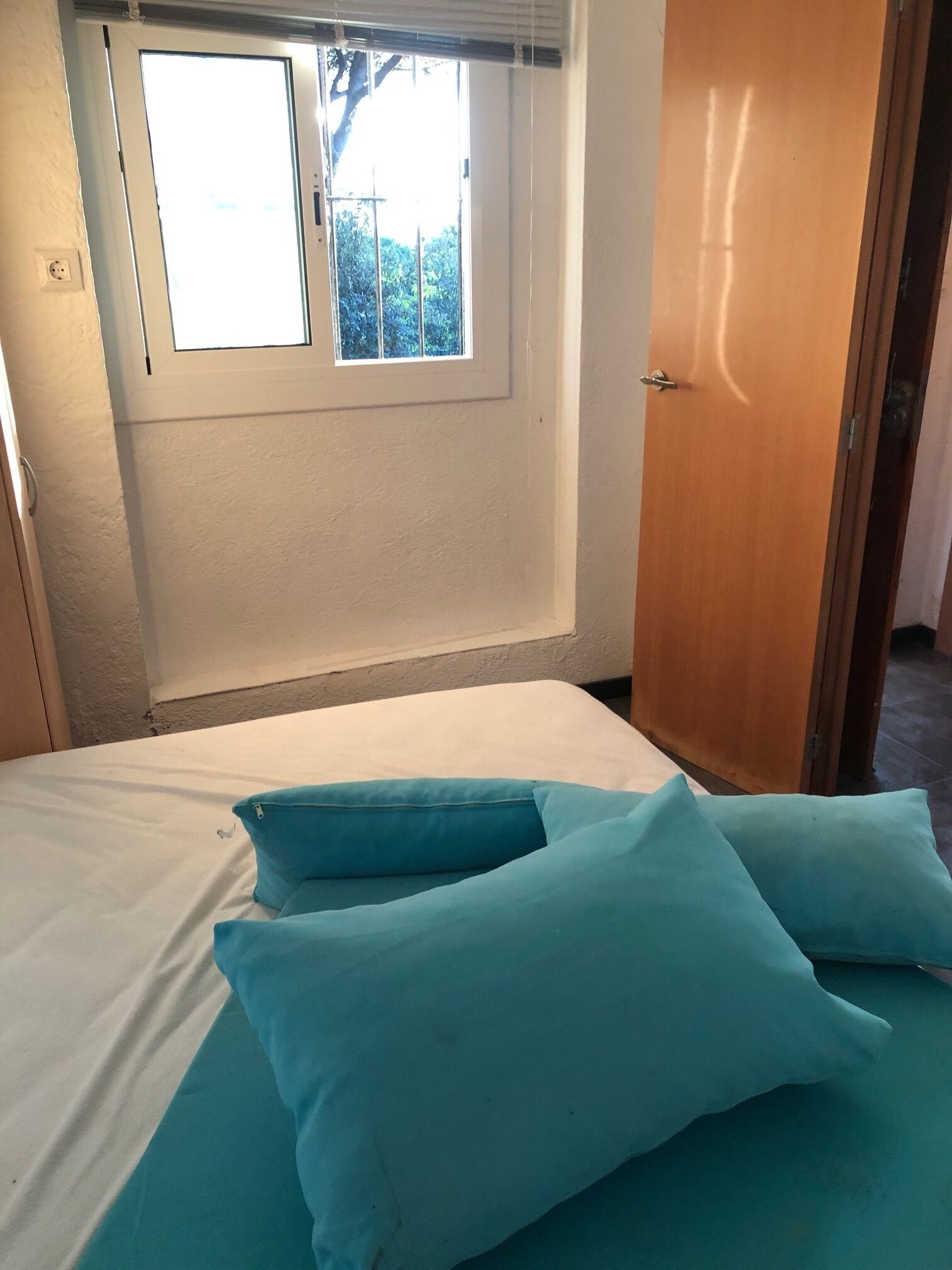Un dormitorio con una cama, una ventana y una puerta.