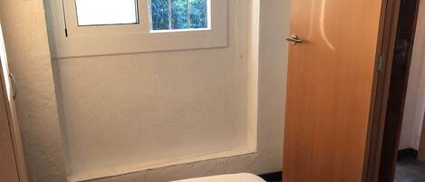 Un dormitorio con una cama, una ventana y una puerta.